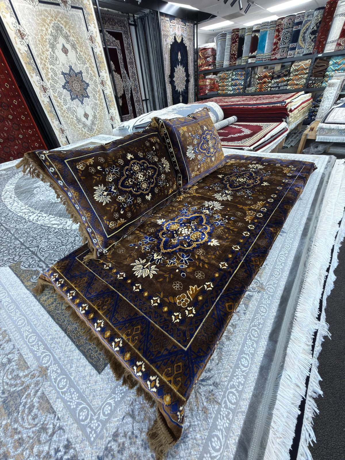 Close angle on the gold flowers and blue zigzag border of the brown Afghan toshak cover