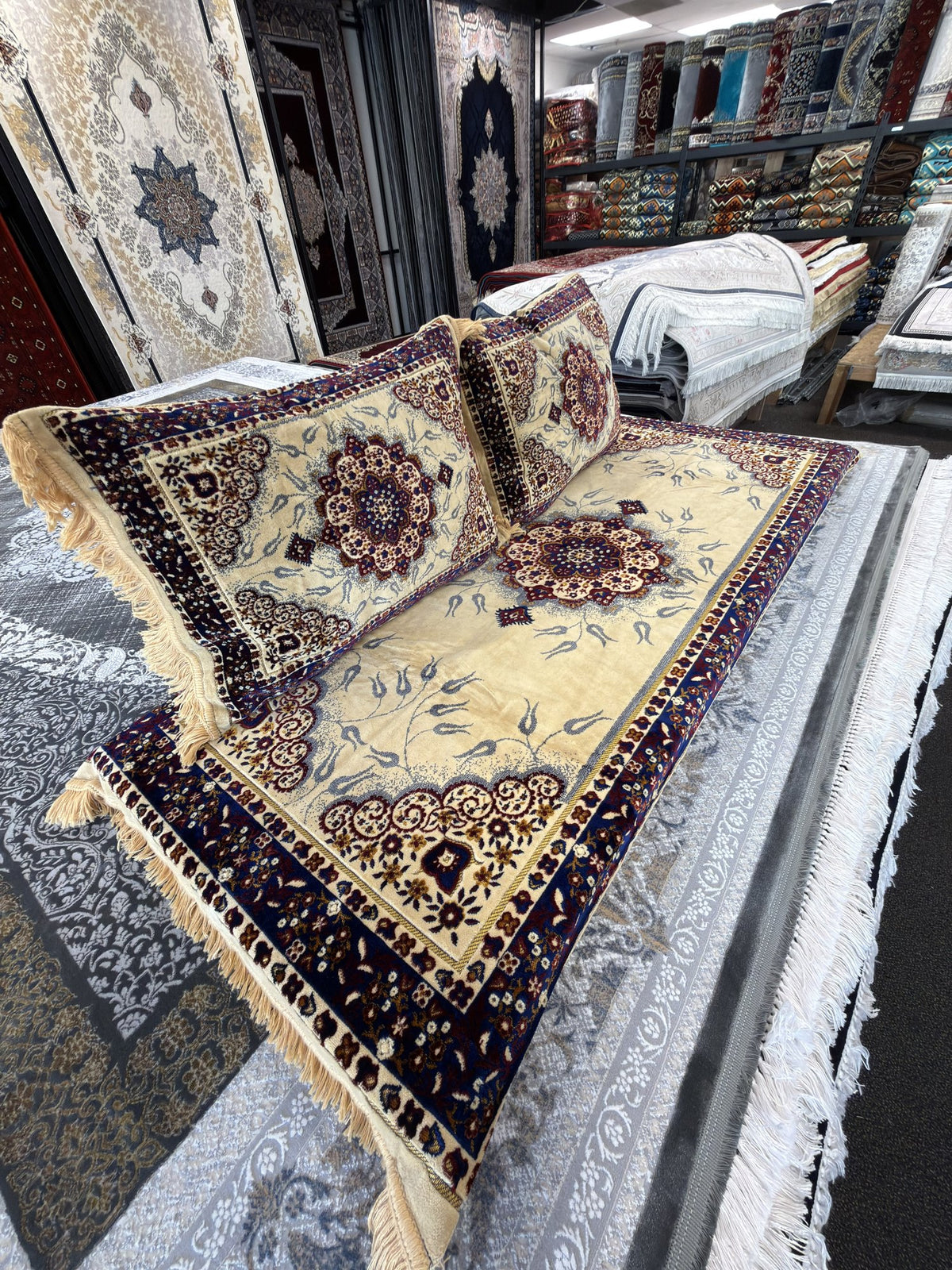 Angled view showing the fringed edge and navy floral border of the cream Afghan toshak