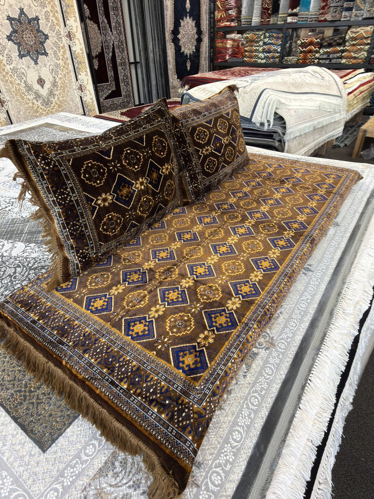 Close view of the repeating Turkmen gul pattern and gold fringe on the brown toshak cover