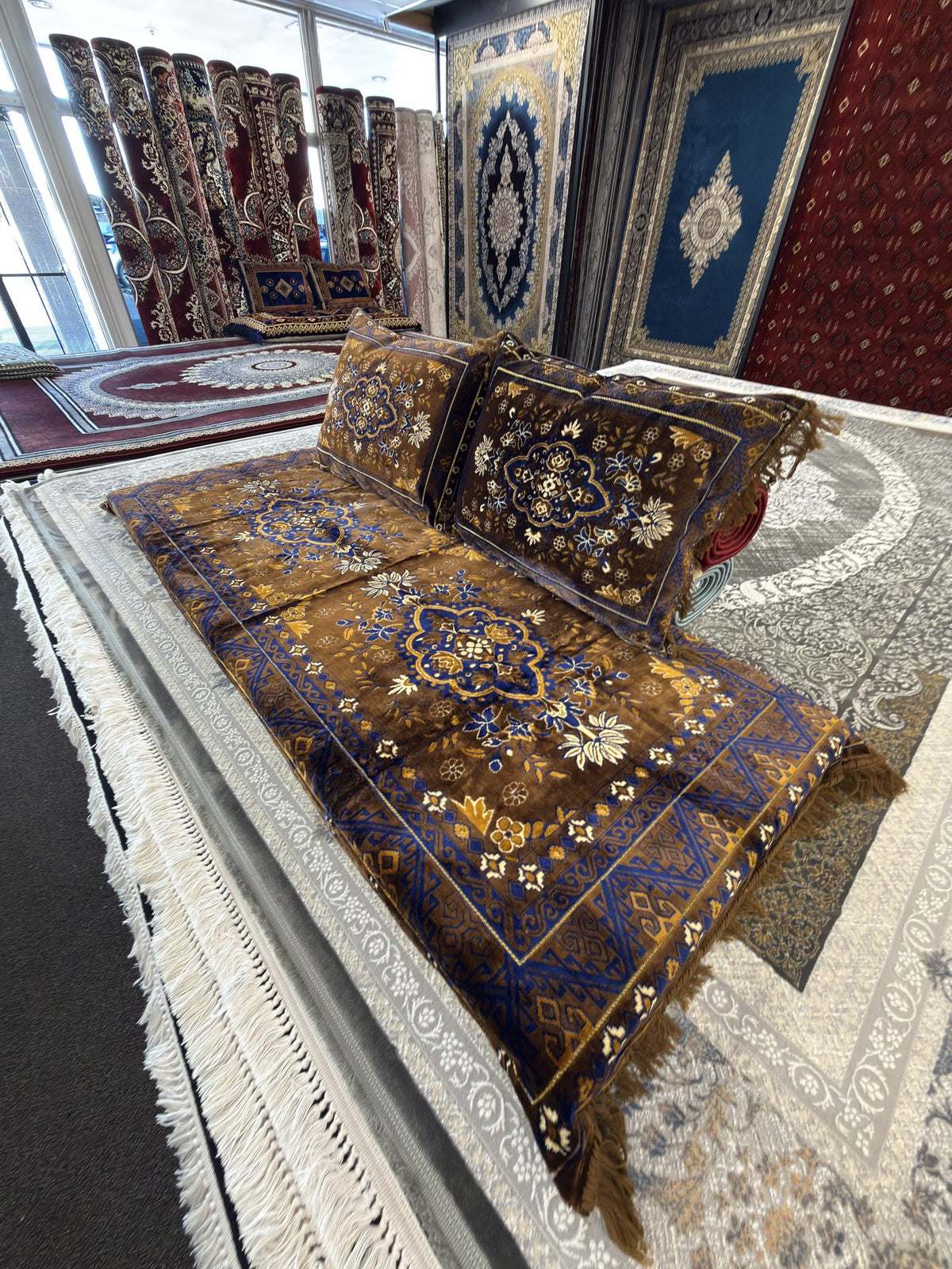 Brown Afghan toshak with royal blue and gold floral medallion, shown from the side with both cushions
