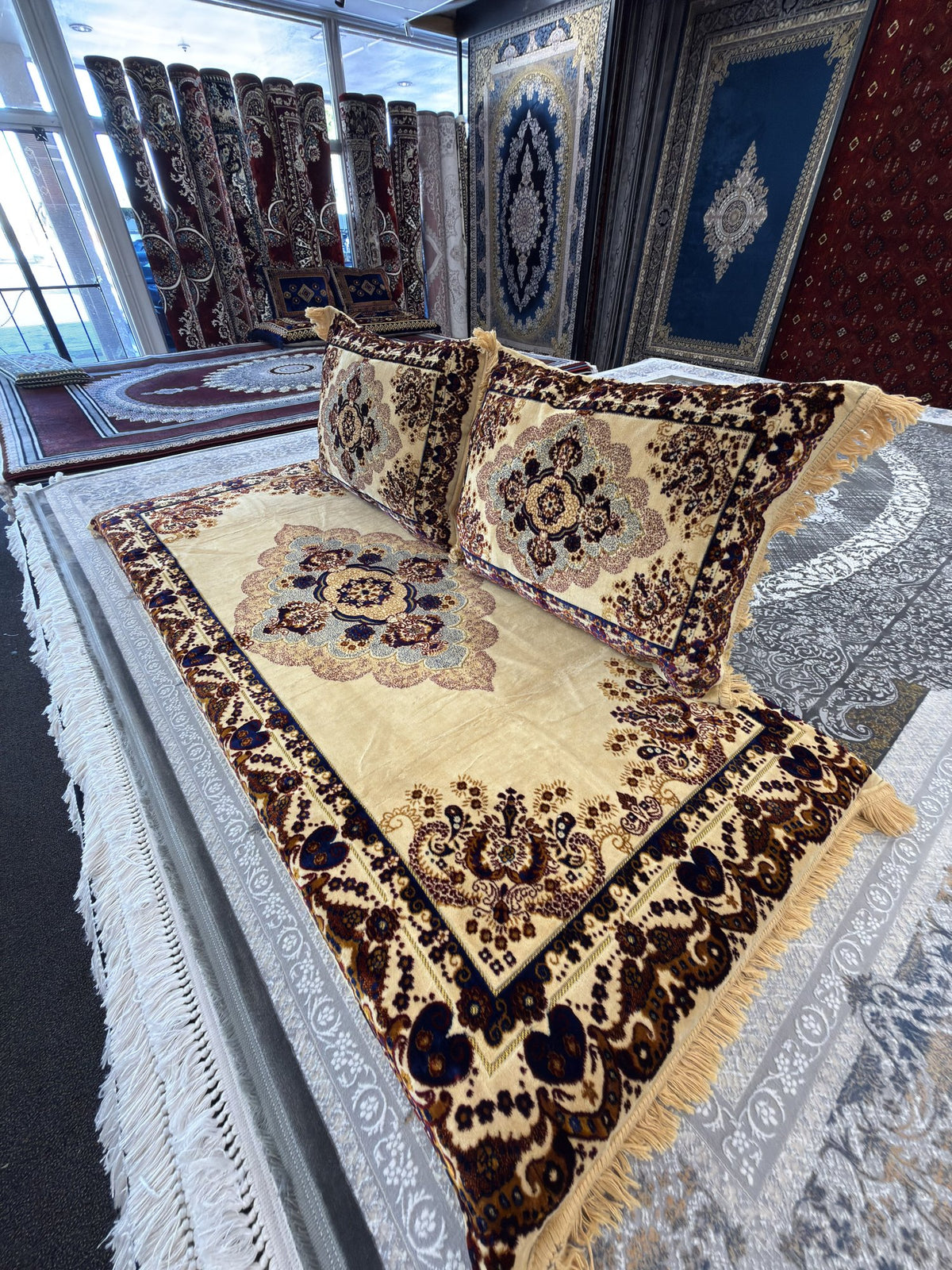 Golden cream Afghan toshak with chocolate brown border, shown at an angle with both cushions