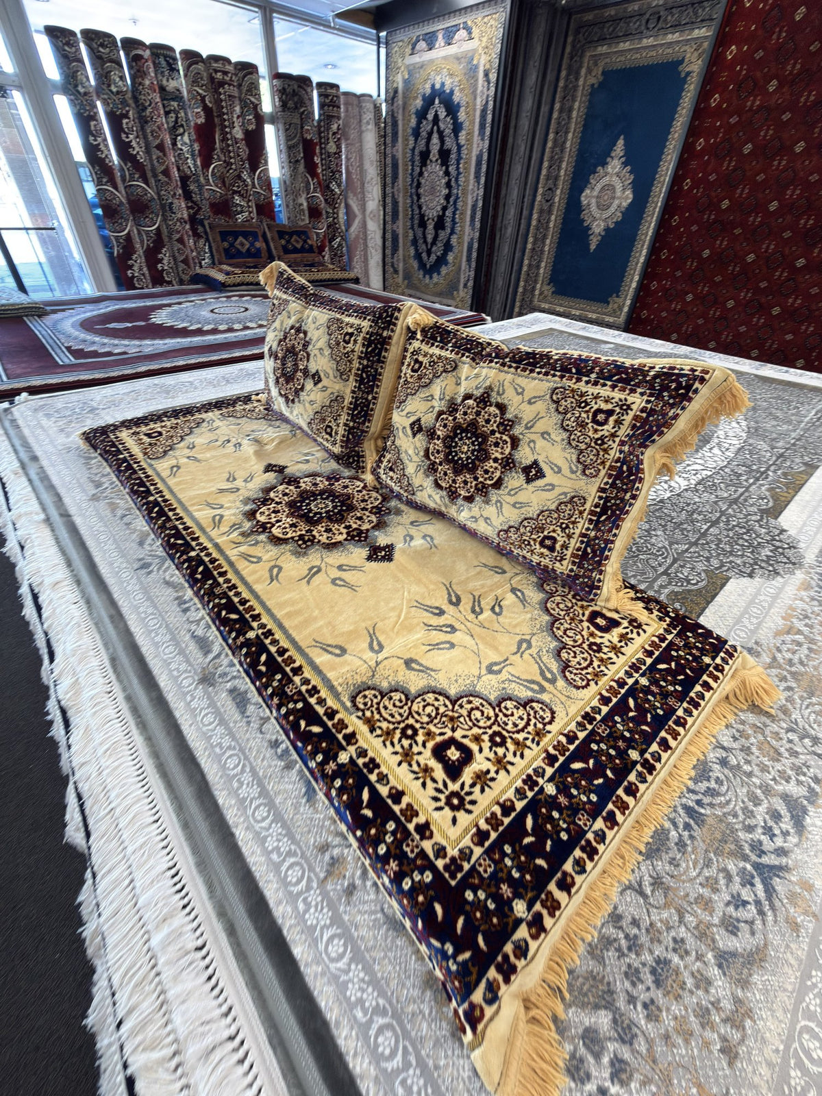 Cream Afghan toshak with navy border and two matching backrest cushions, side view